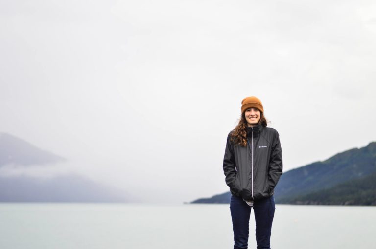 An image of Sarah Buckleitner, standing in front of the ocean and mountains in Alaska.