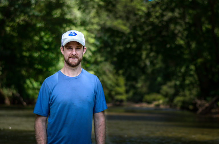 A photo of Phillip Bumpers, standing in a stream, wearing a blue shirt.