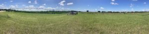 A man in a button-down shirt leads a group of students toward a center pivot irrigation system.