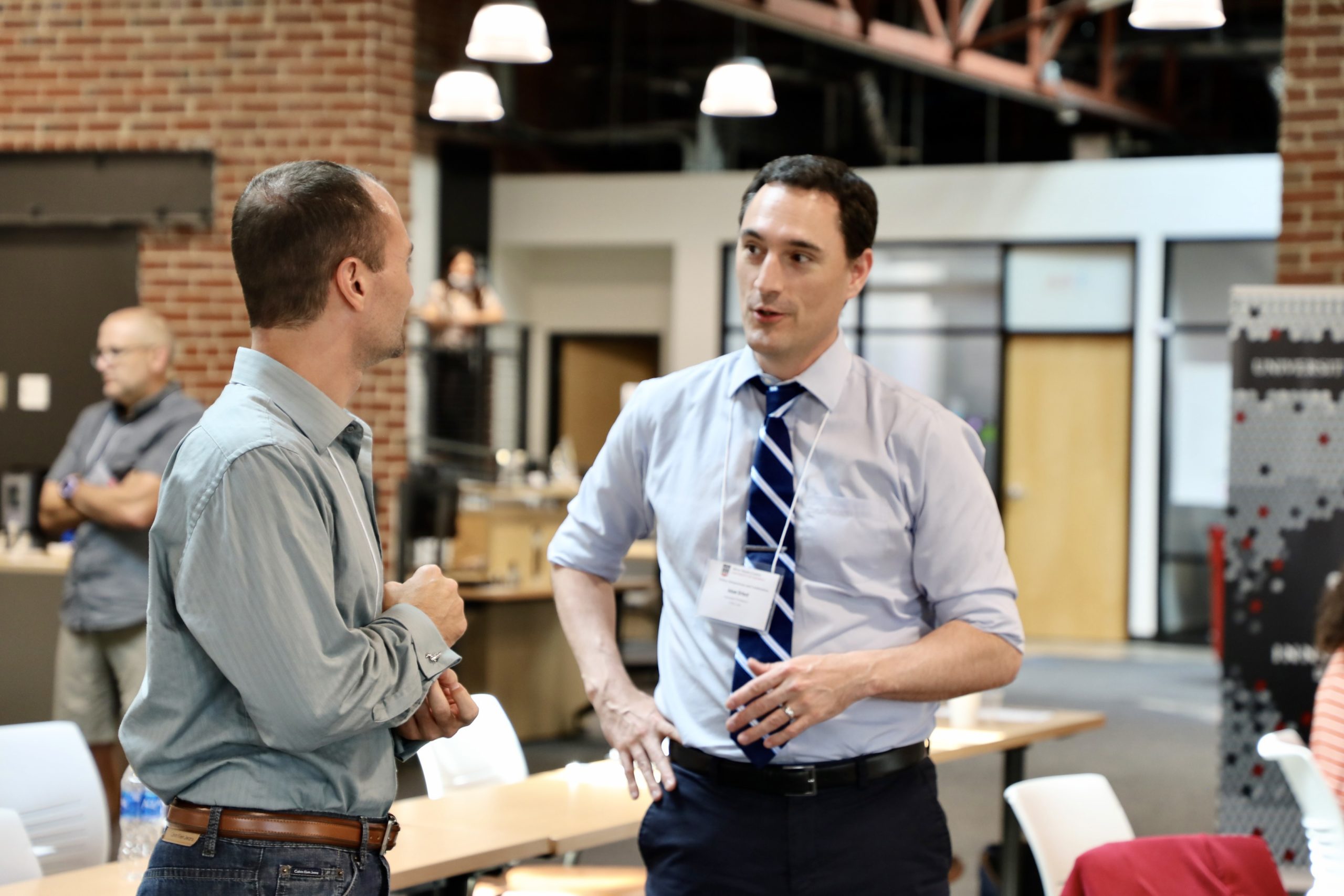 Two men converse in button downs.