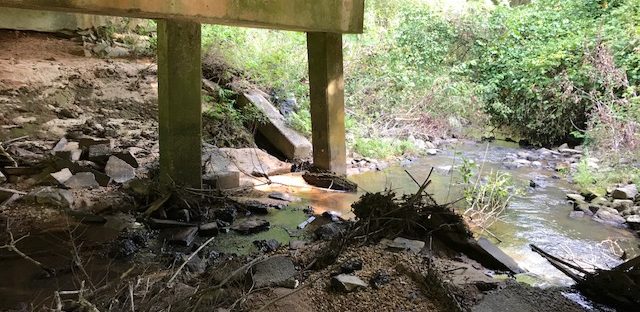 A river and the underside of a bridge are visible.