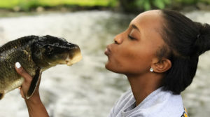 Carleisha Hanns holds a fish, pretending to kiss it.