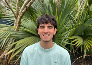 Gabriel Stephenson smiles in front of palmettos.