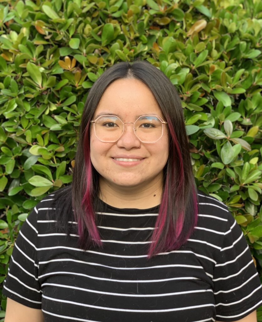 A woman wearing glasses smiles.