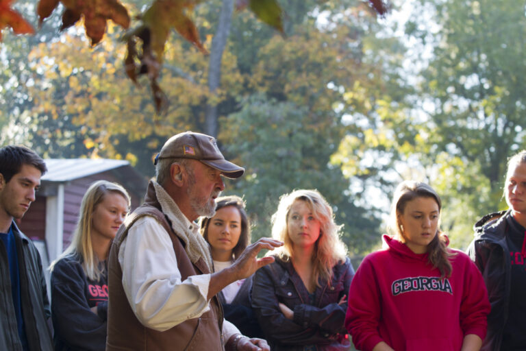 A man teaches to a class of students outside.