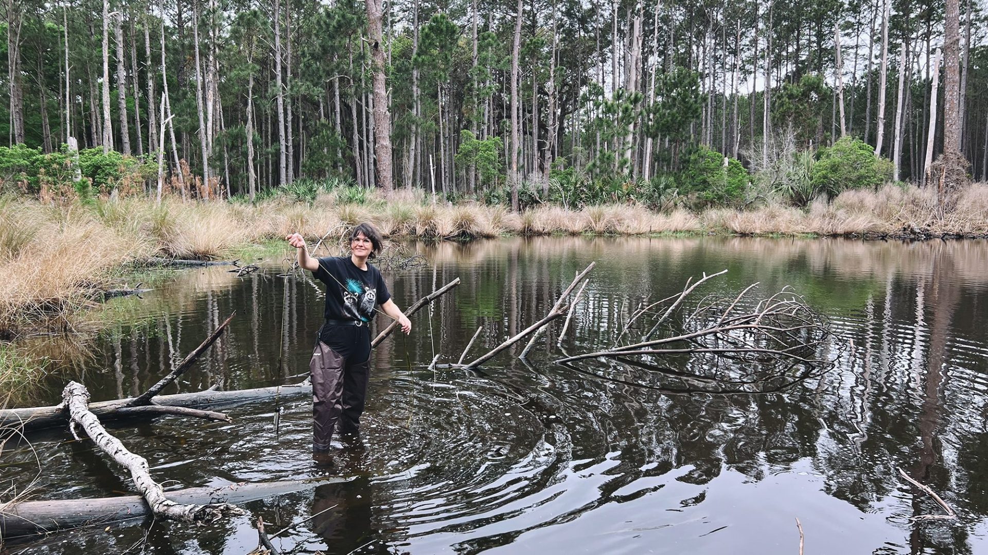 Charlotte Garing standing in a pond taking monitoring samples.