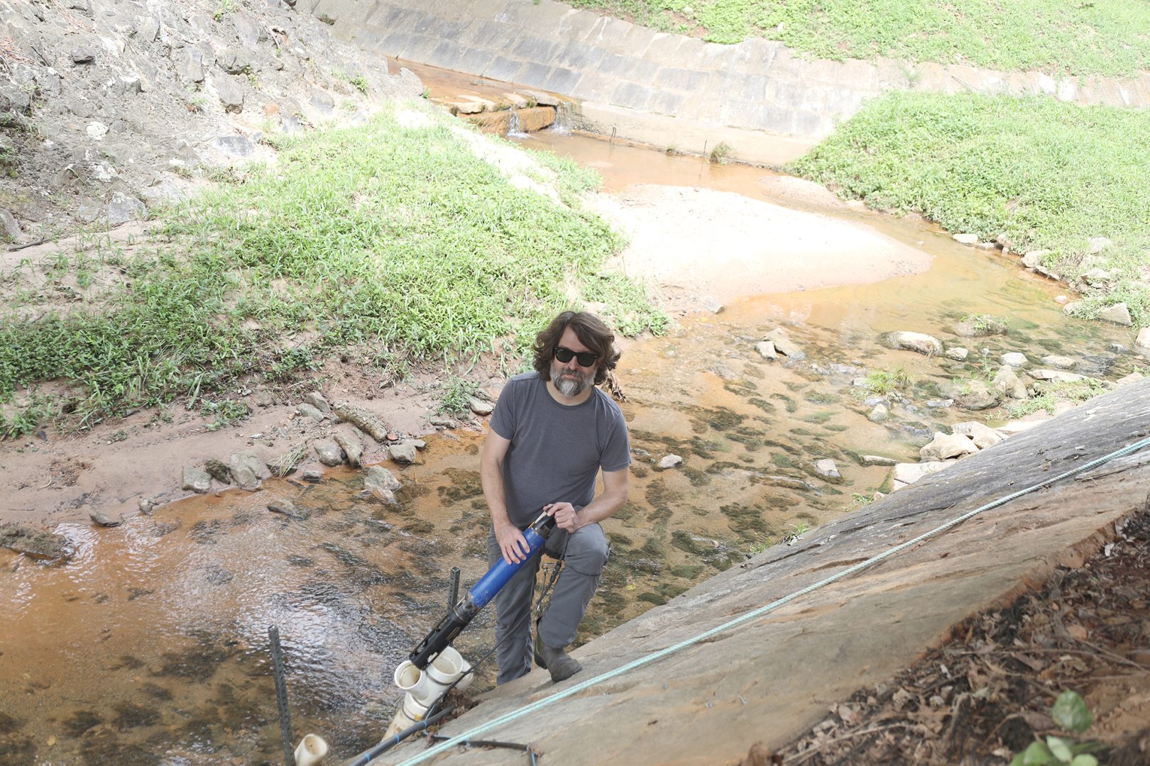 Franklin Leach holds monitoring equipment in Tanyard Creek on the University of Georgia campus.
