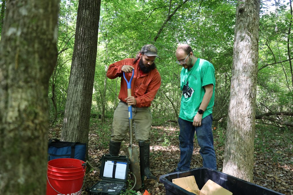 Two student researchers take a soil sample