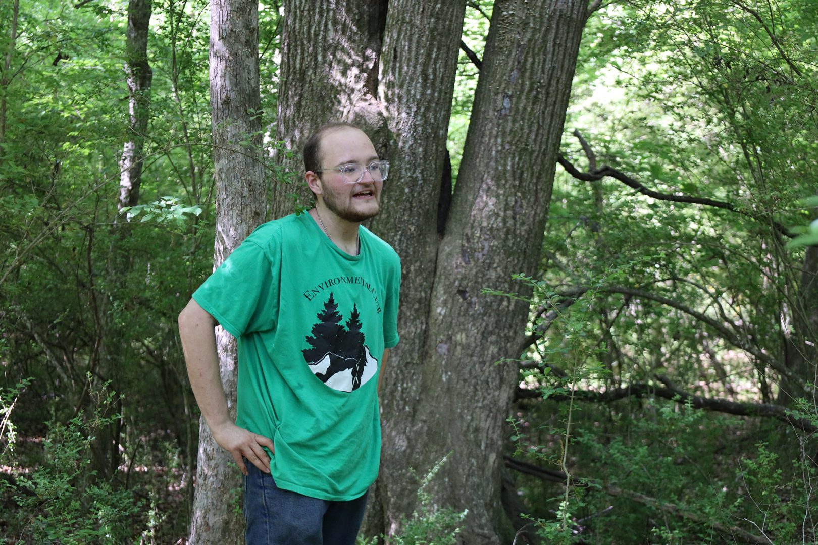 Graduate student stands in the forest